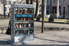 Ein Bücherschrank aus Metall, der auf einem öffentlichen Platz steht. 